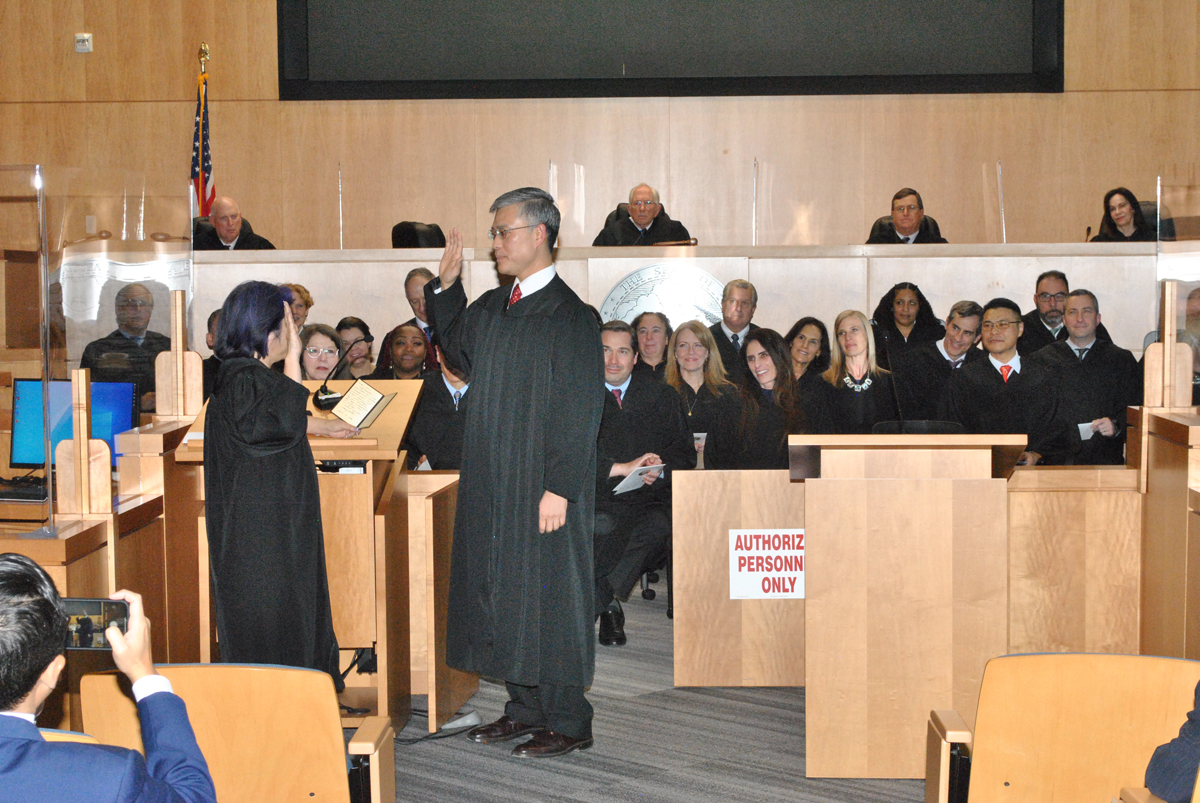 New Judge Peter Chang takes the oath of office from Judge Joni Hiramoto.