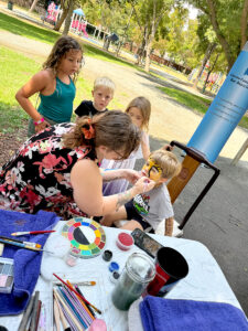 woman painting the face of a child in the park