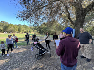 Person making announcements to group outdoors in a park