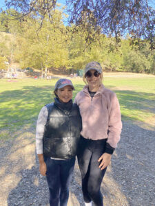 Two women outdoors wearing jackets and baseball hats