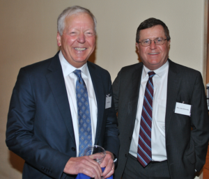 Two men dressed in suits smile for camera.